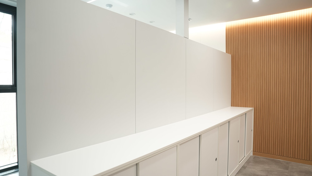 White film on a partition wall and a run of low cabinets, with an oak slatted feature wall beside them