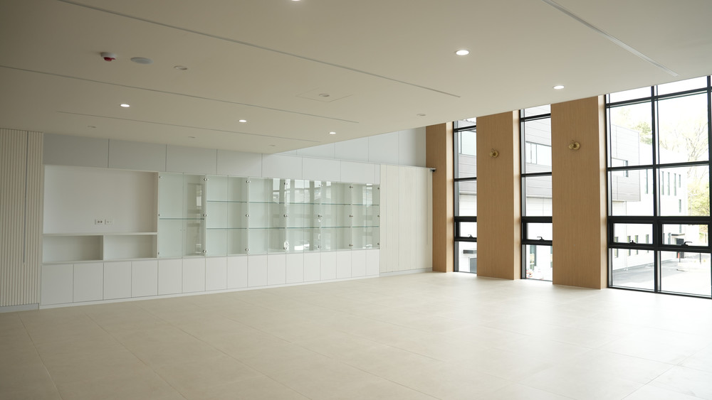 Large hall with a white storage wall, glass display cabinets and oak-clad window piers