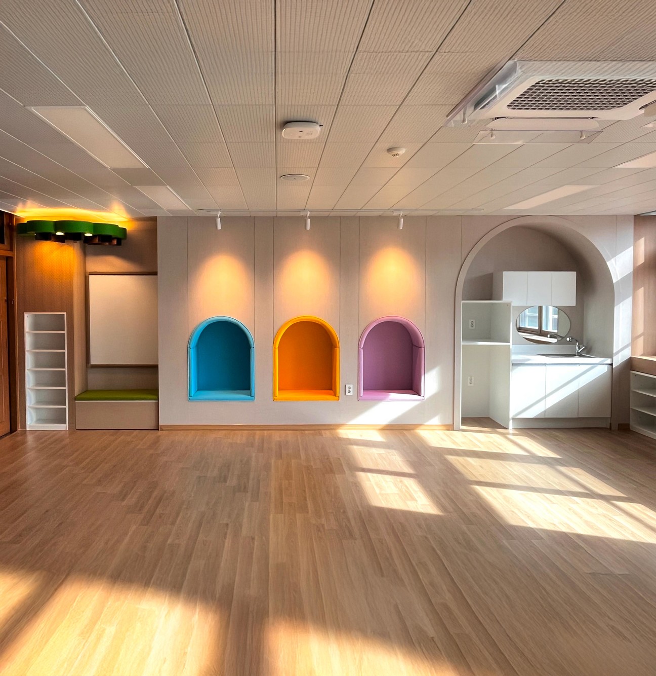 Three arched reading nooks in a classroom, lined in blue, orange and purple film