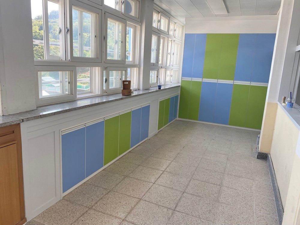 Blue and green film on the fronts of built-in cabinets under a classroom window